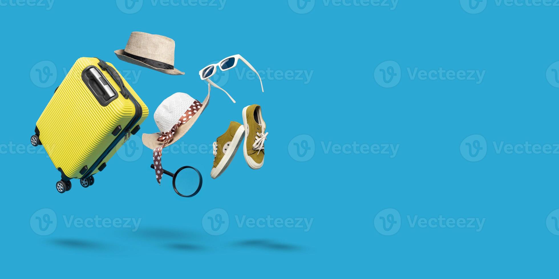 maleta azul con gafas de sol, sombrero y zapatos sobre fondo azul pastel. concepto de viaje estilo minimalista foto