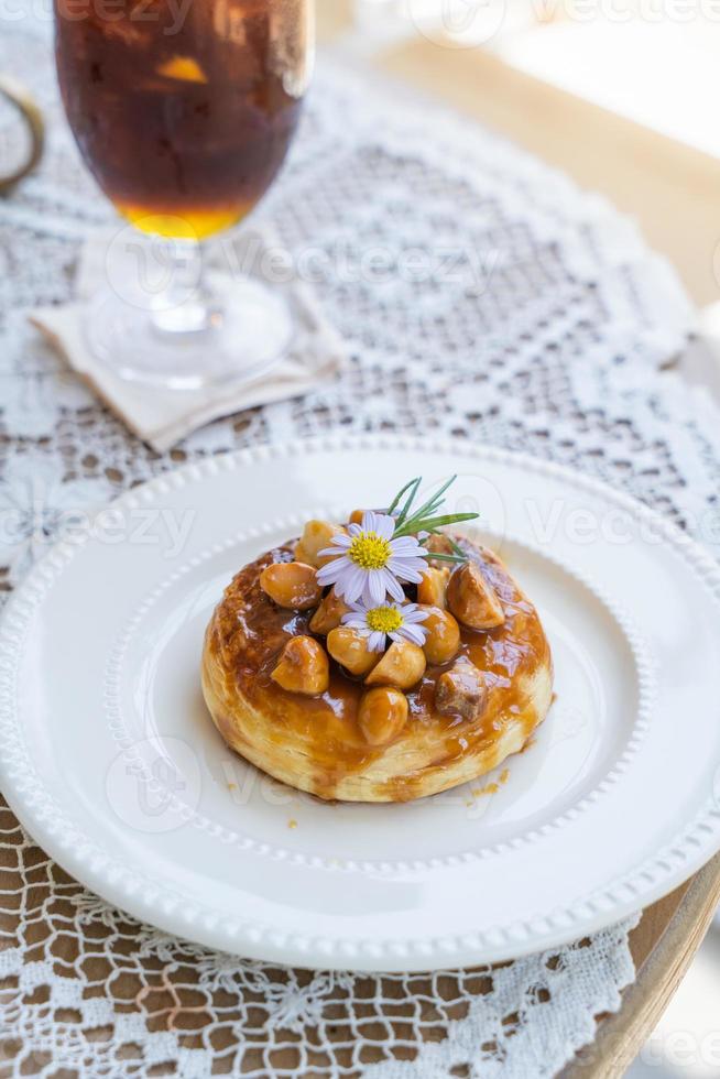 Homemade puff pastry deep fried donuts or cronuts in stack with sugar standing on white plate over table top with lace tablecloth. croissant and doughnut topping with macadamia nut and caramel sauce. photo