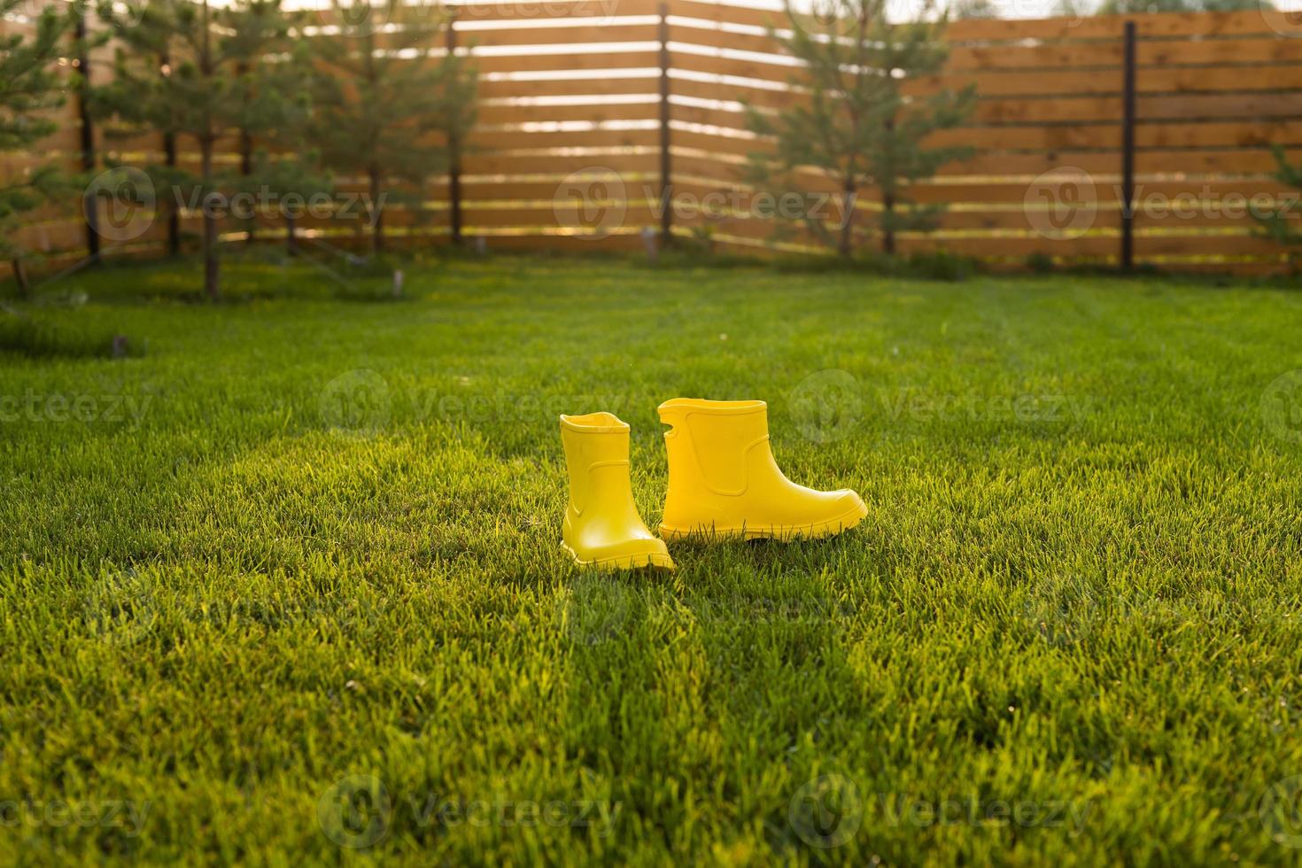 Yellow boots stands on green lawn in spring garden copy space and place for advertising - summer and country life concept photo