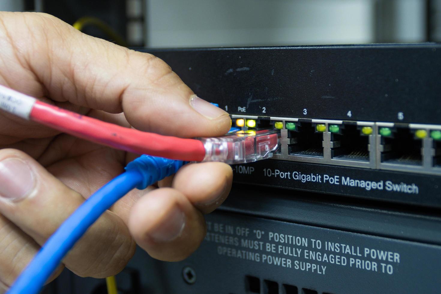 Hand of a man holding The network cables to connect the port of a switch to connect internet network, concept Communication technology photo