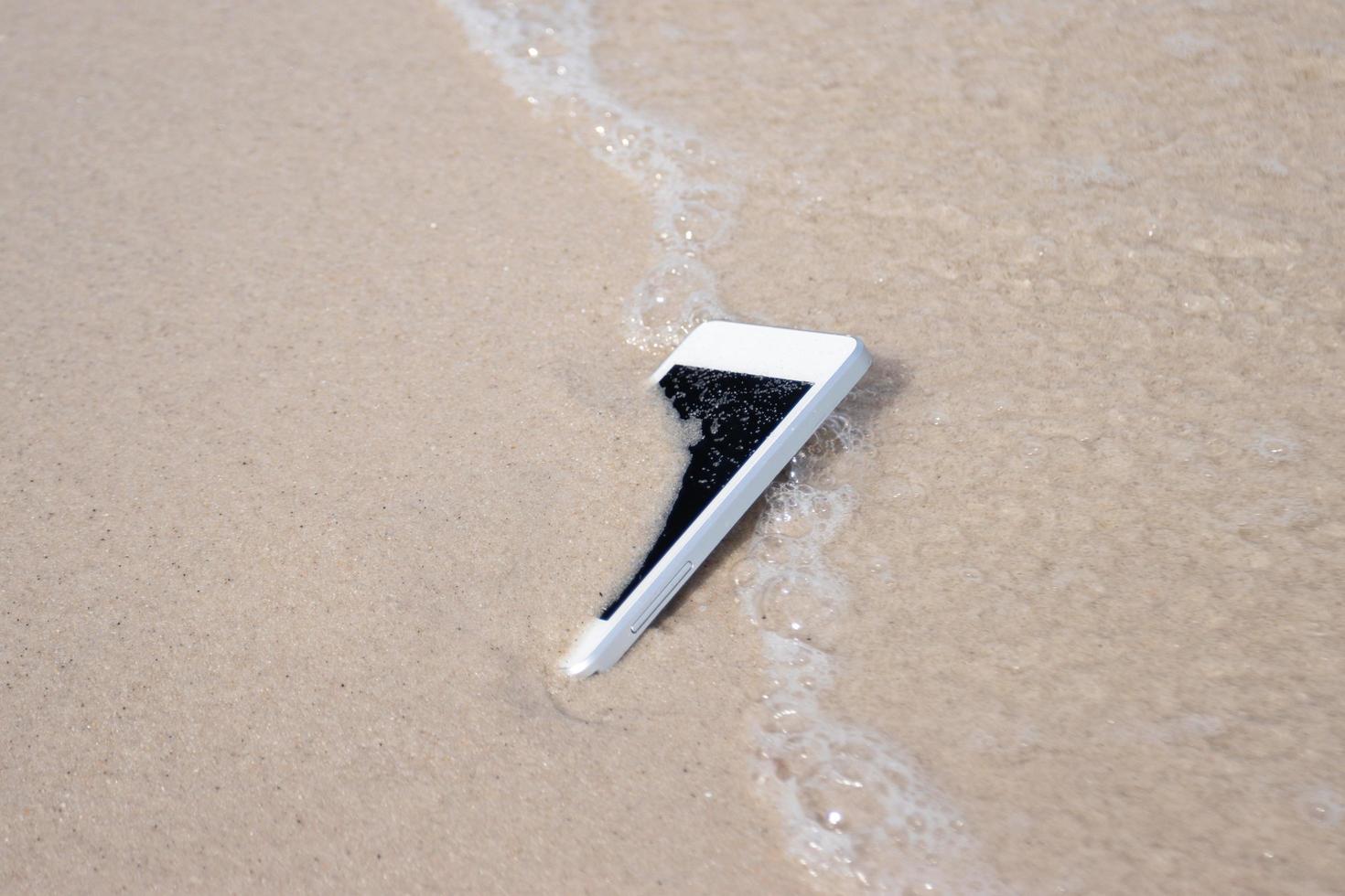 White Mobile phone on sand at beach concept electronic waste photo