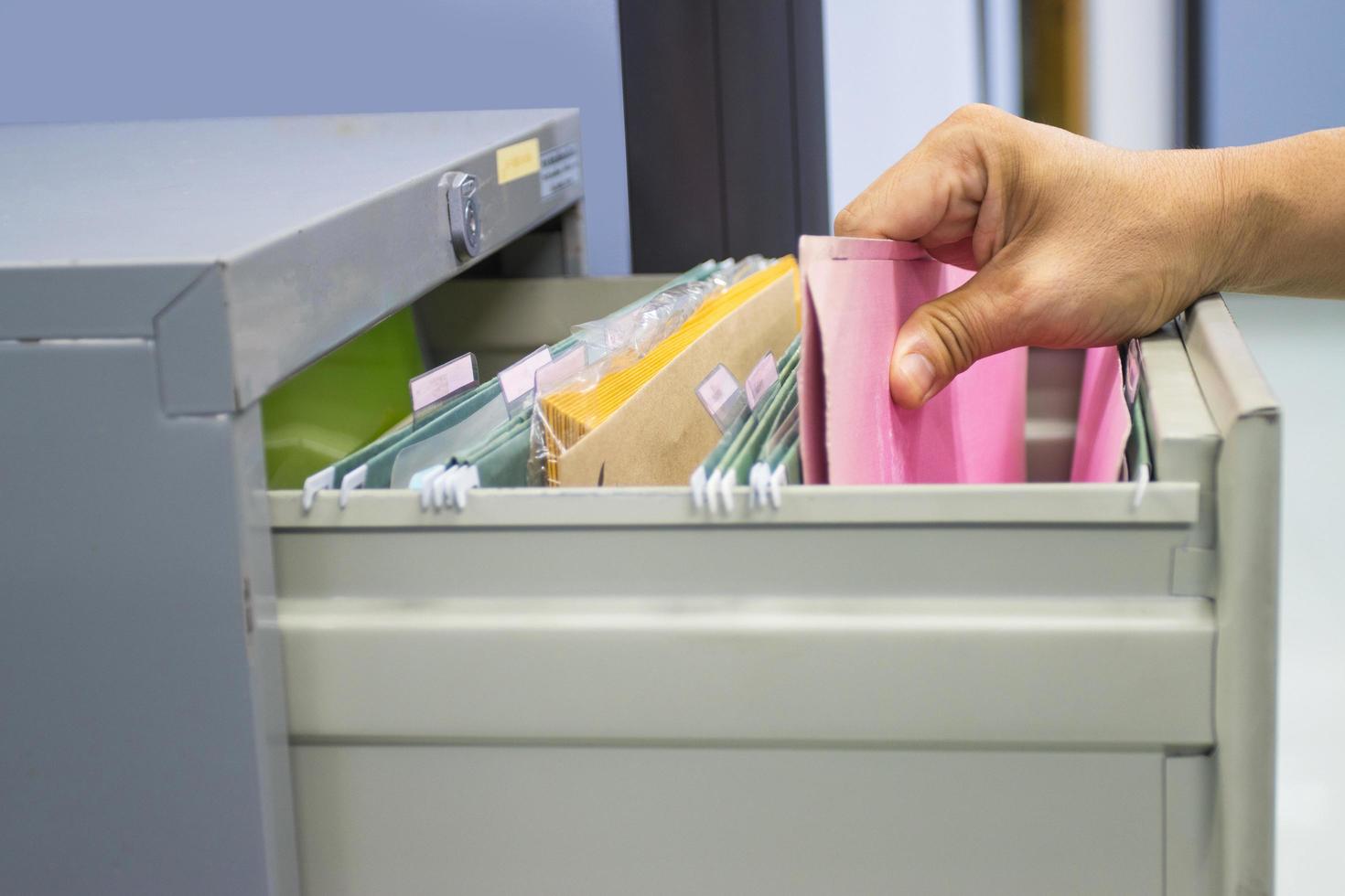 mano del hombre busca documentos de archivos en un archivador en la oficina de trabajo foto