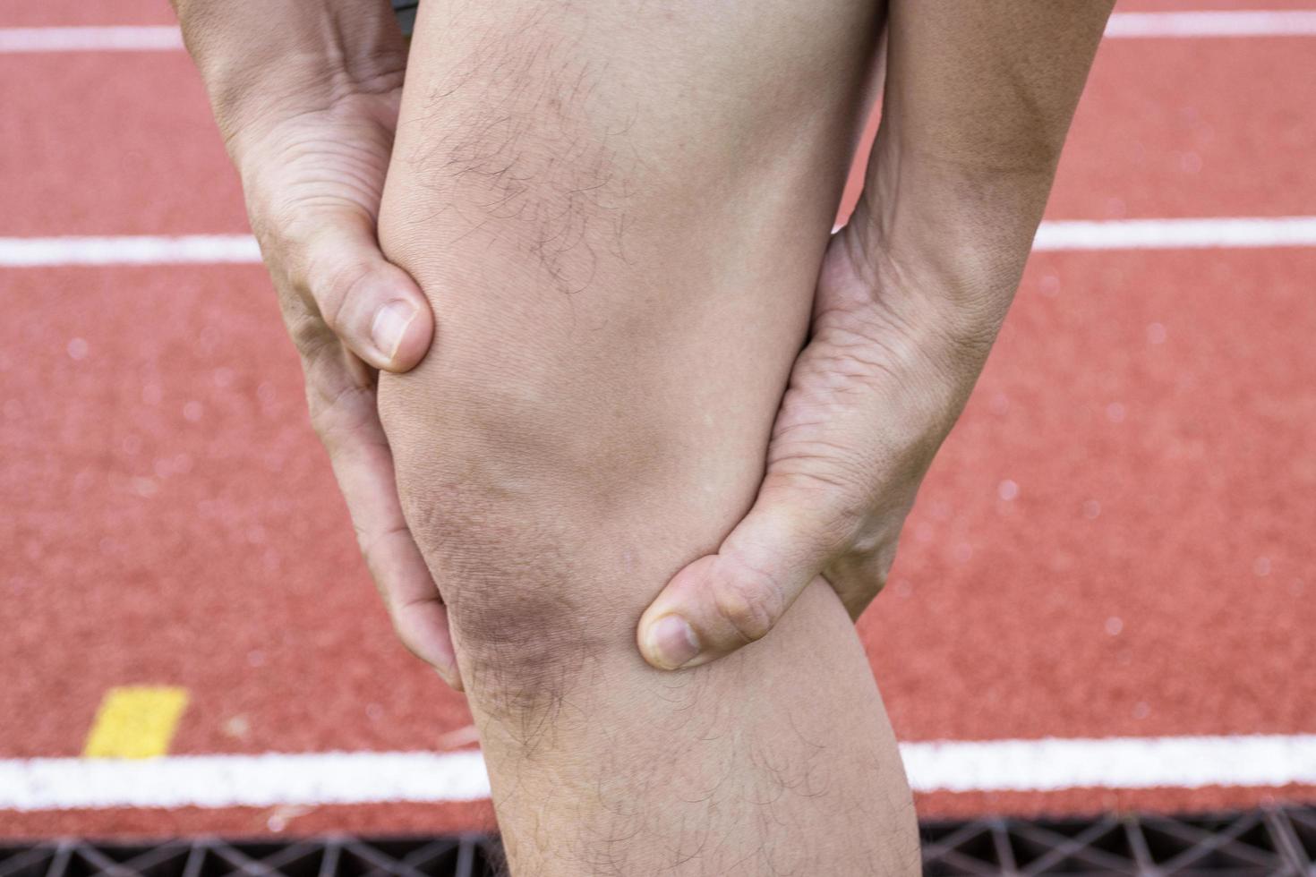 Problemas en las articulaciones de la rodilla del tendón en la pierna del hombre debido al ejercicio en el estadio. foto