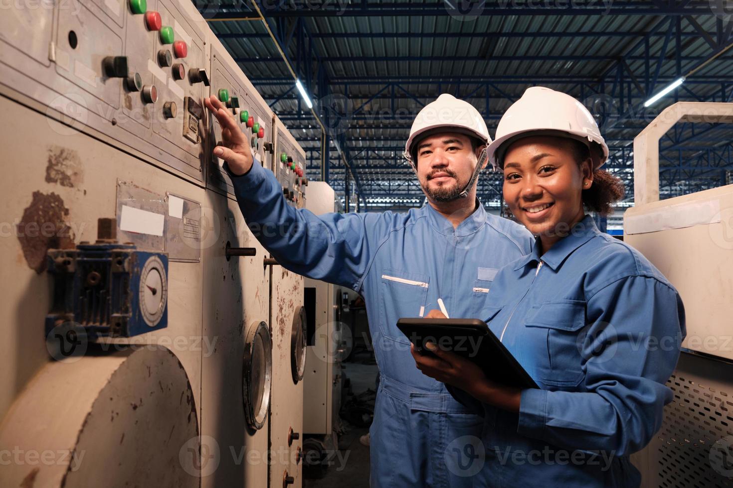 Portrait of two professional industry engineers partner in hard hats and safety uniforms looking at camera and smile, inspect and maintenance check machine in manufacture factory, service occupation. photo