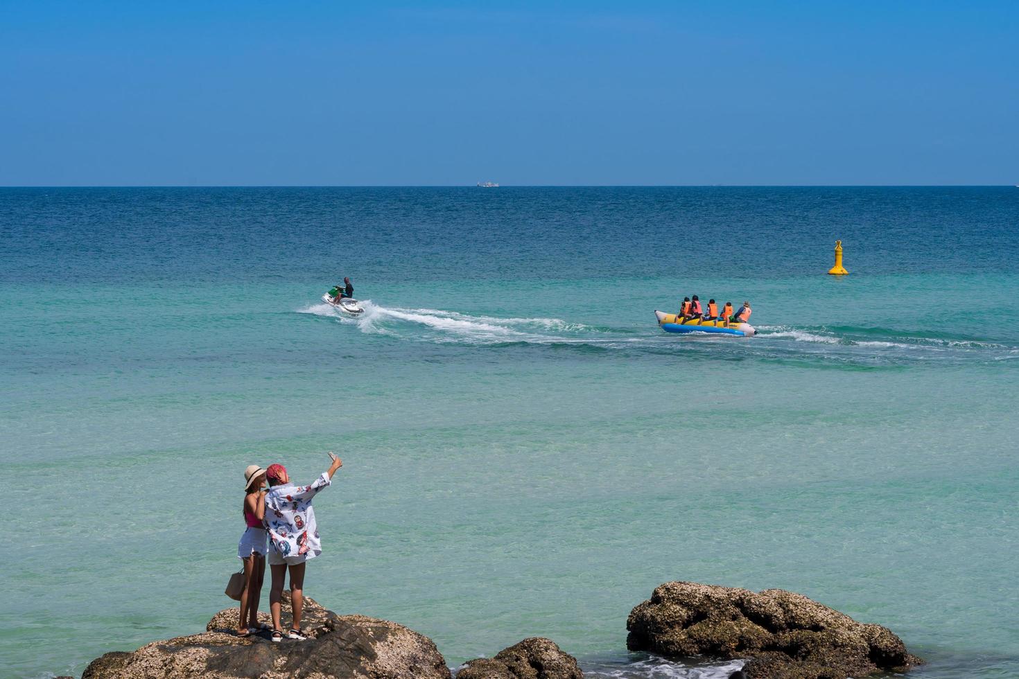 chonburi, tailandia - 29 de marzo de 2021, la gente disfruta de actividades en la hermosa playa de mar azul claro en verano, juega en un bote banana, toma fotos selfie, se relaja y calma el océano, la playa de thian, la isla de koh larn