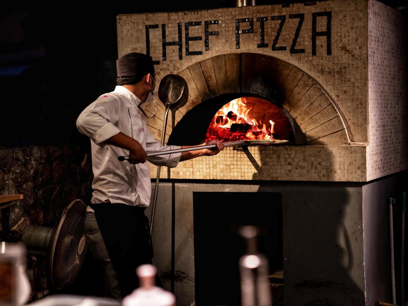 prachuap khiri khan, tailandia - 31 de enero de 2021 hombre haciendo pizza con estufa en el mercado de cigarras foto