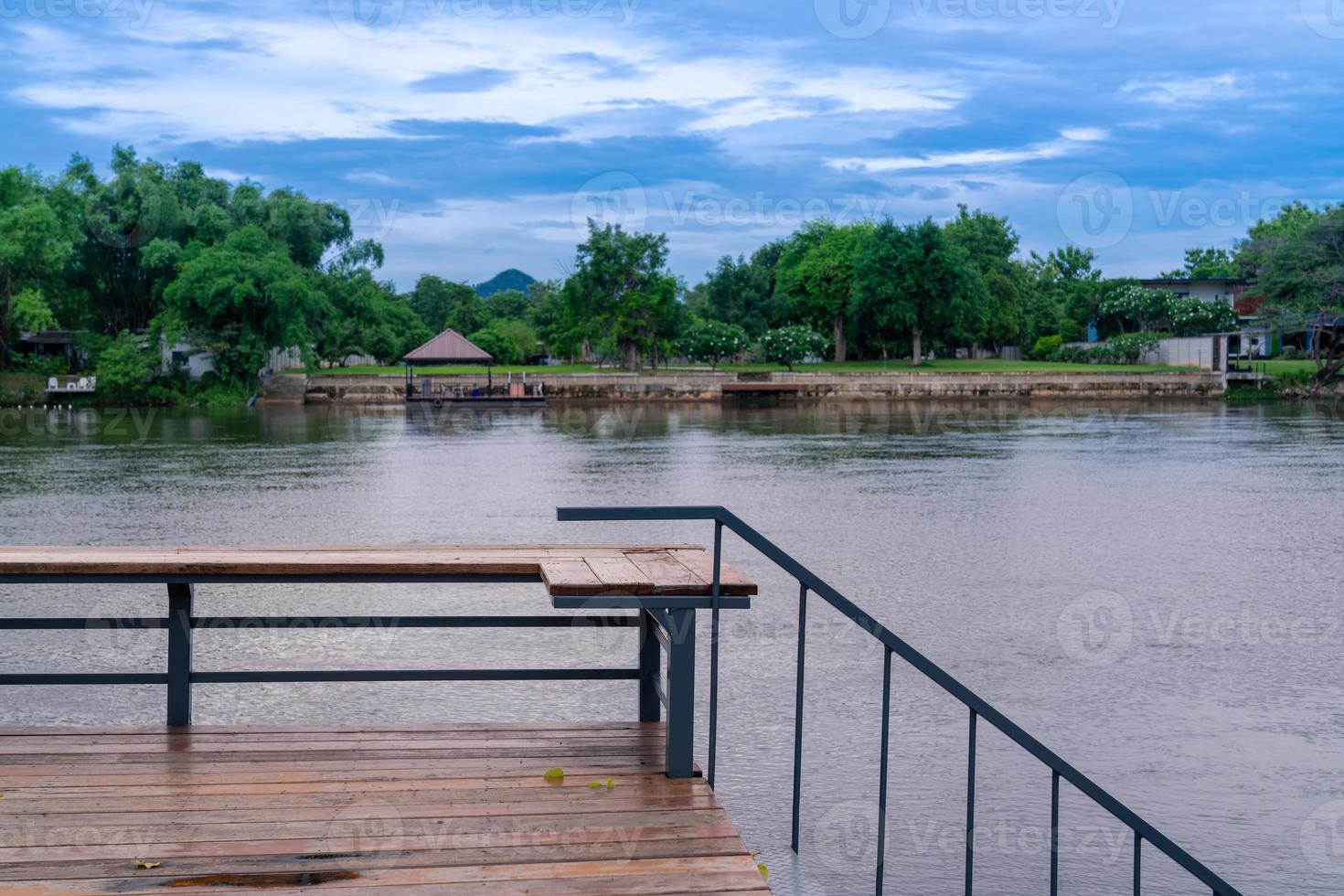 terraza con asientos de madera con vista al río kwai, costa tranquila con bosque verde y fresco foto