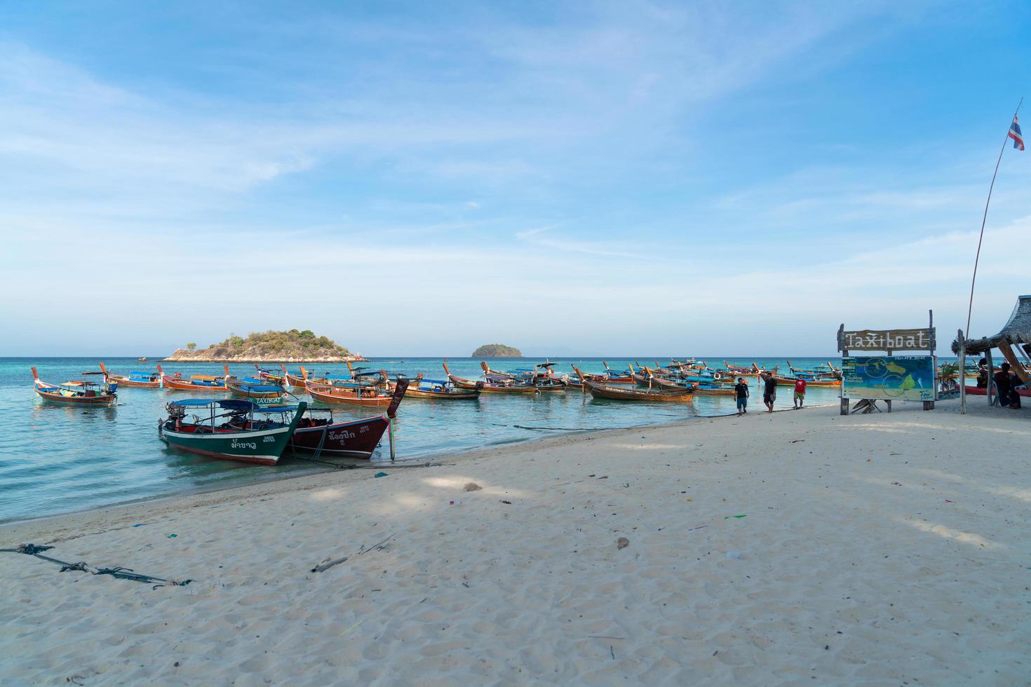 satun, tailandia - 3 de marzo de 2021 muchos botes de cola larga de madera en el mar azul en el área de botes de taxi en la playa del amanecer en la isla de lipe, satun, tailandia, pacífica vista al mar escénica, transporte de viaje tradicional foto