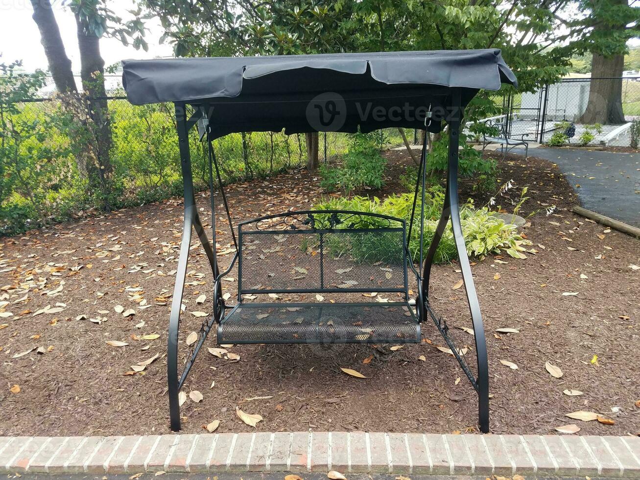 black metal covered swing with brown mulch photo