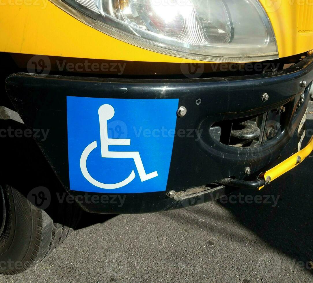 blue wheelchair symbol or sign on yellow school bus bumper photo