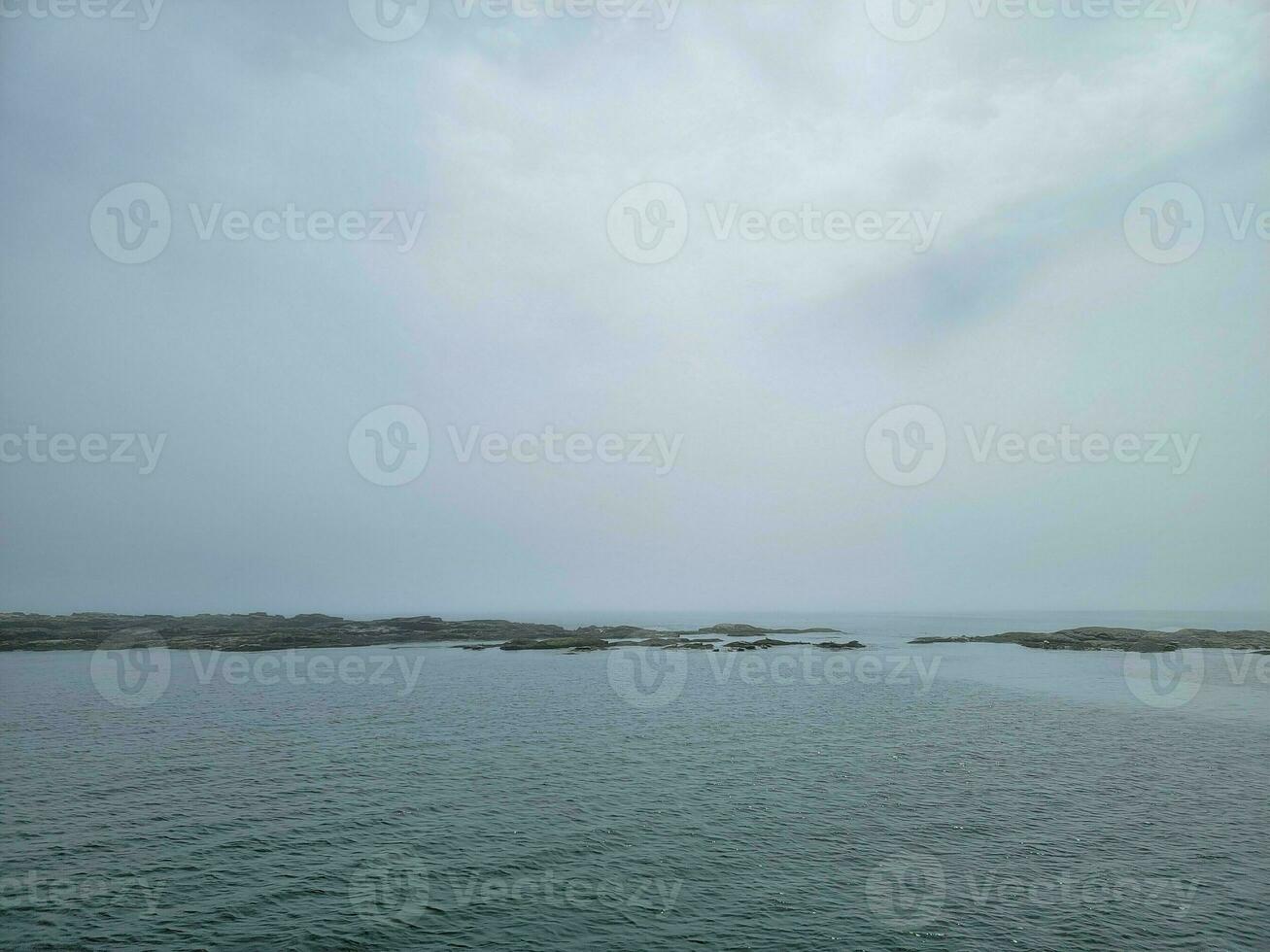 rocky shore on the coast in Maine with water and clouds photo
