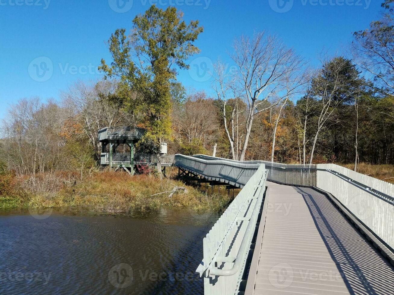 boardwalk trail with fence and wood tower or lookout with water photo