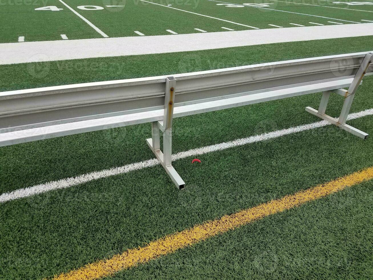 metal bench on football field with red mouthpiece photo