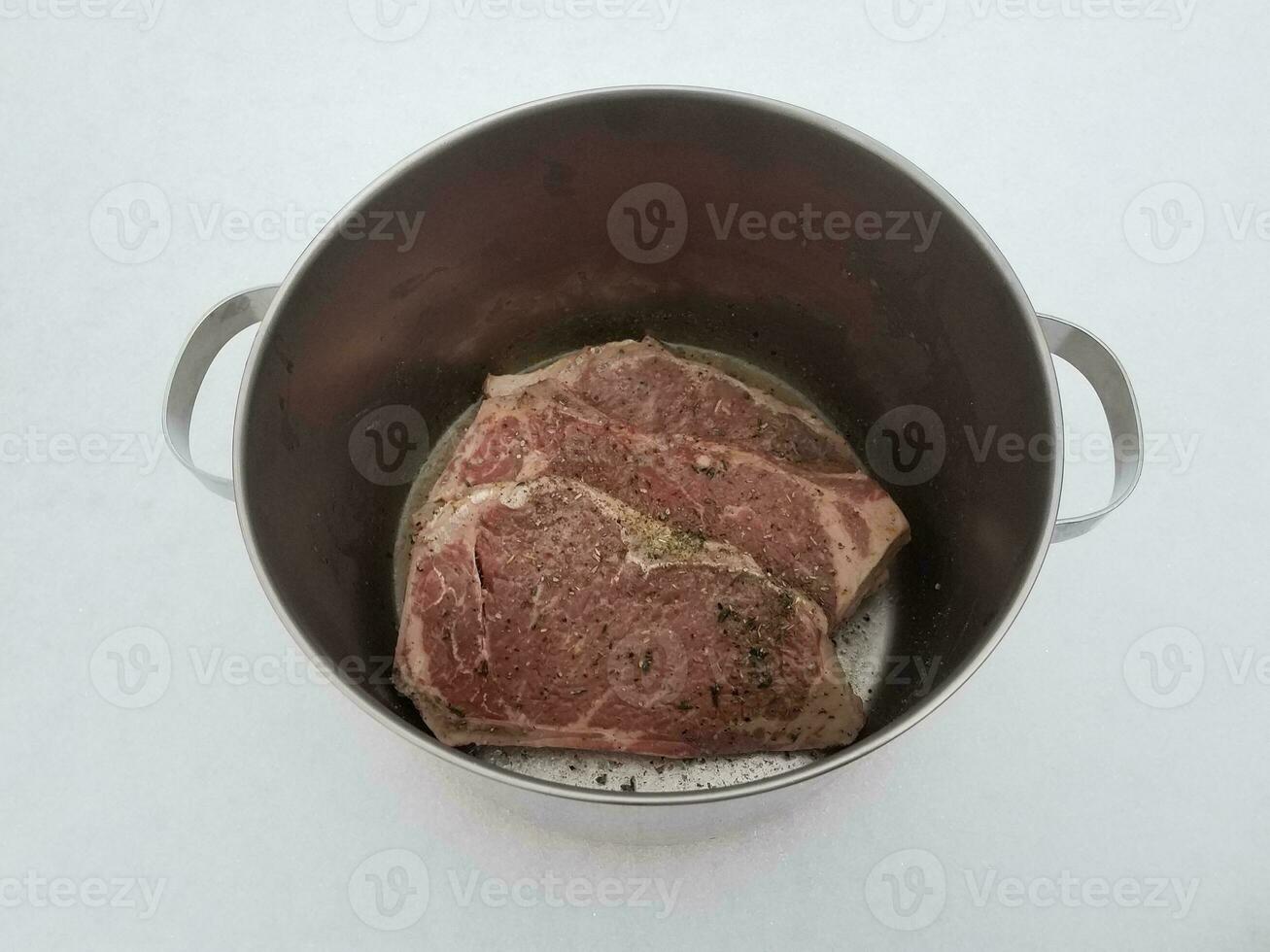 beef steak with seasoning and liquid in metal pot on snow photo