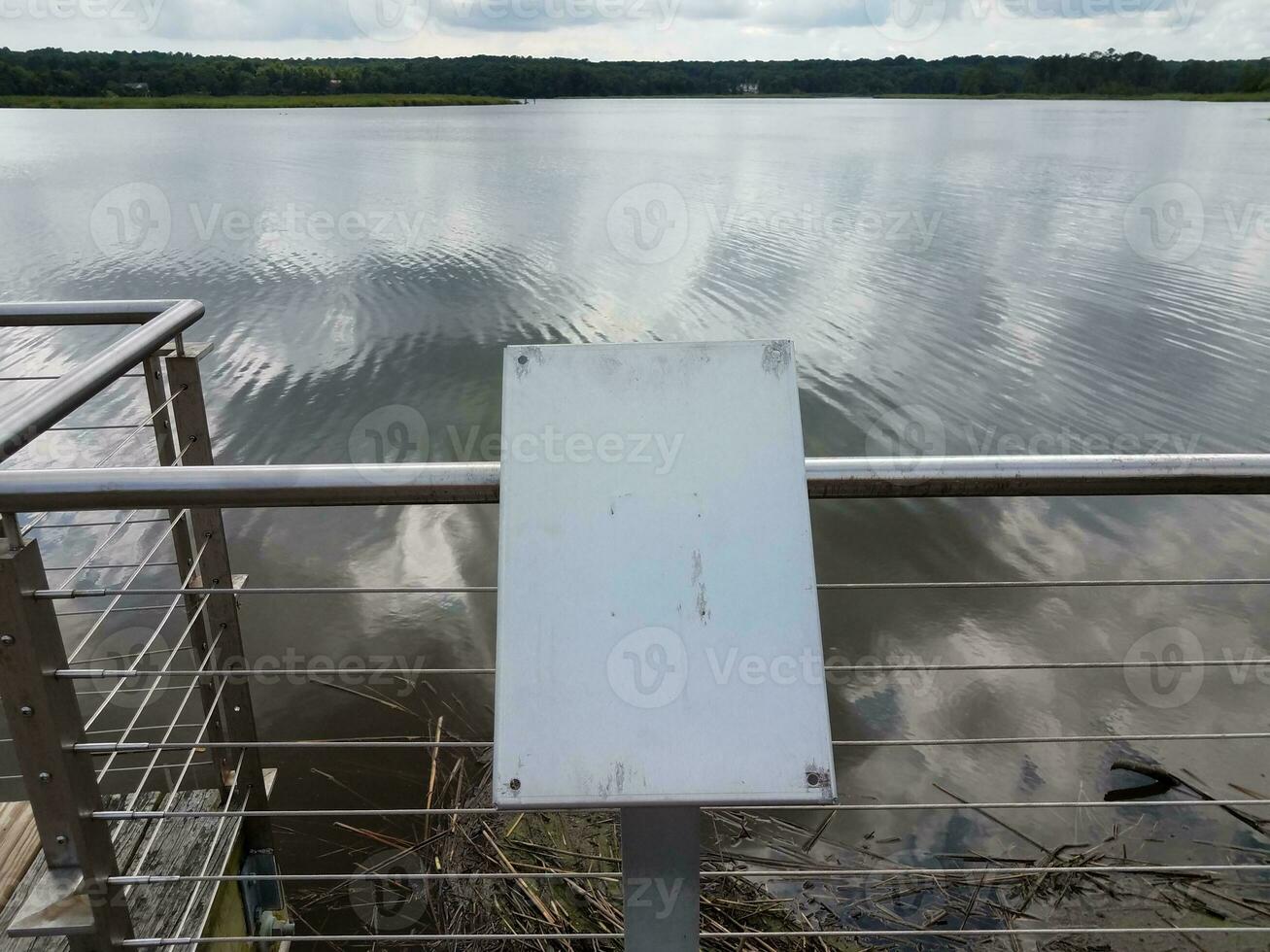 blank and worn metal plaque on railing with river water photo