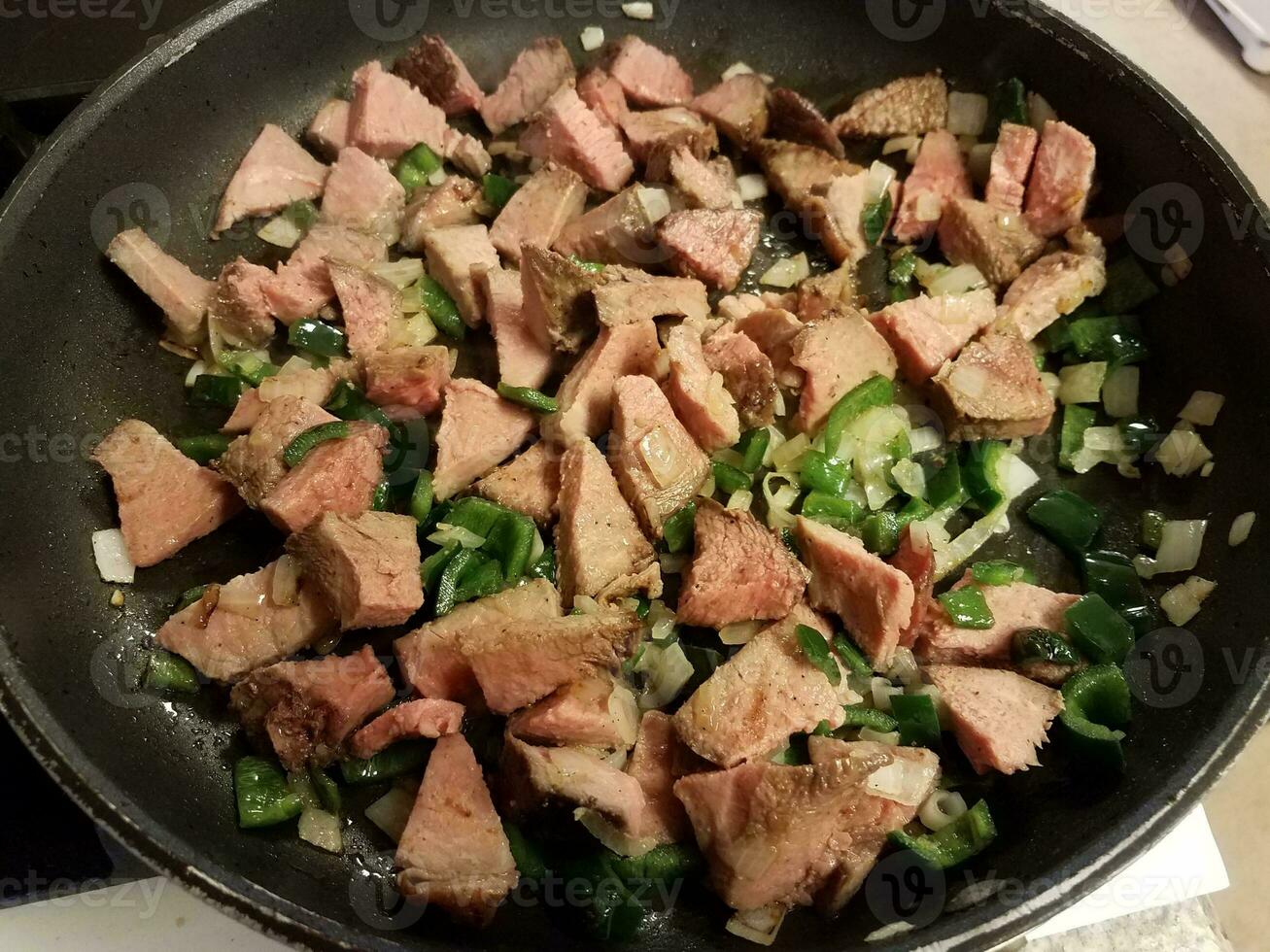 beef and hot peppers and onions in frying pan photo