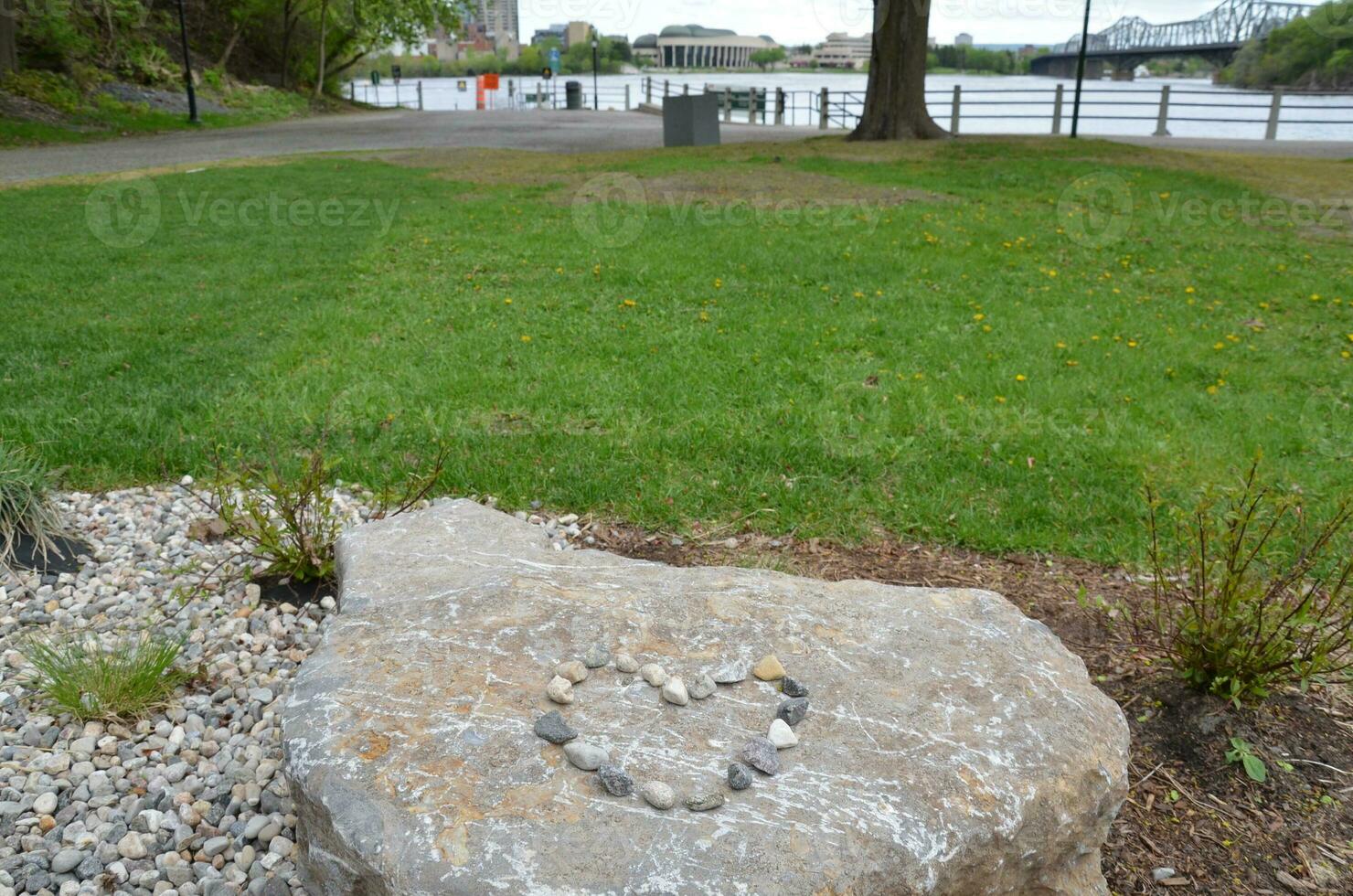 heart shape on boulder with rocks and grey tiles and water photo