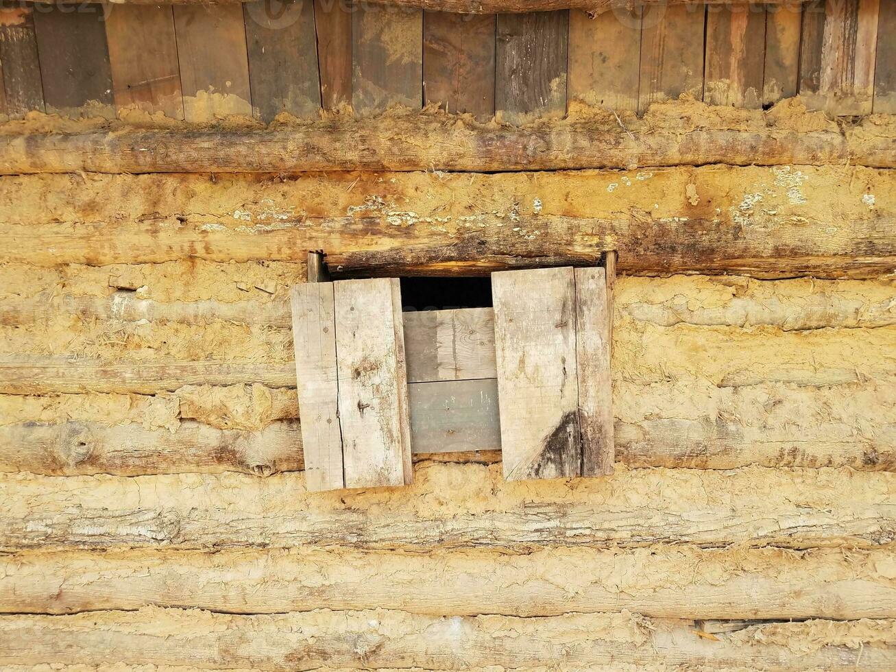 boarded window on old log and mud cabin photo