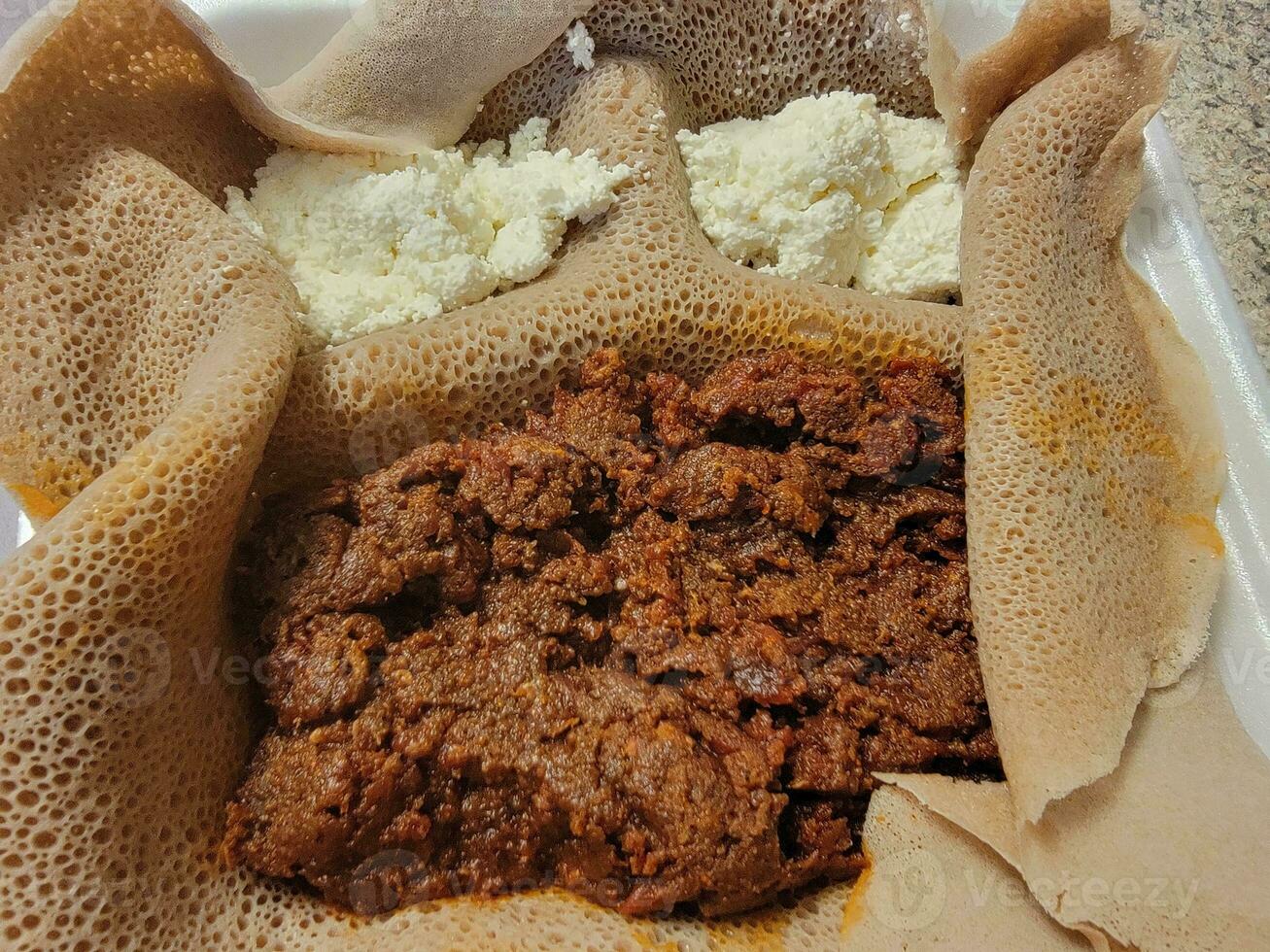 comida etíope kitfo carne cruda con pan injera y queso foto