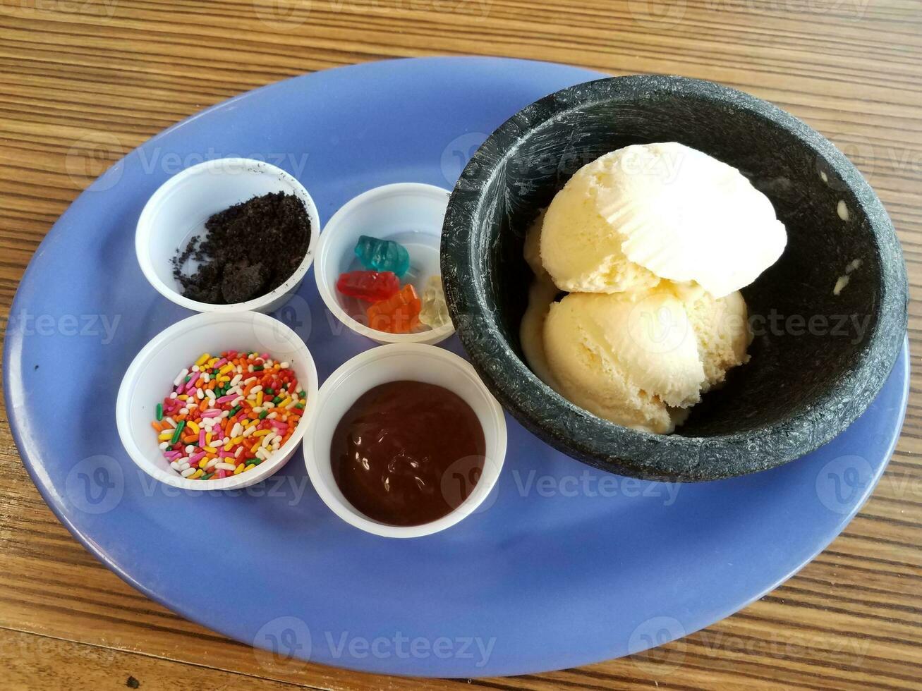 vanilla ice cream with sprinkles and chocolate on blue plate photo