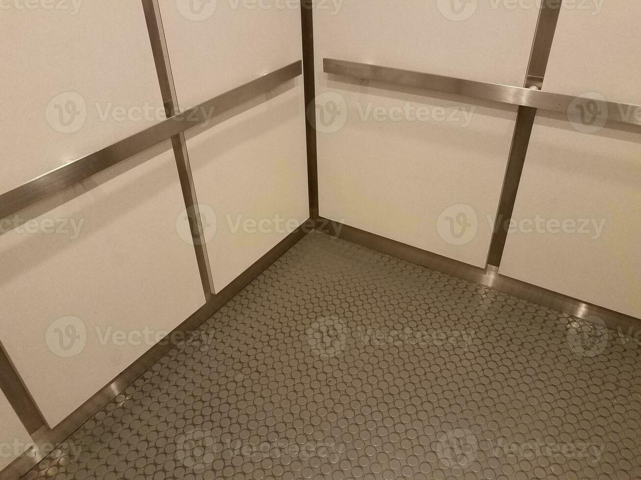 interior of elevator with grey floor and metal bars and white walls photo