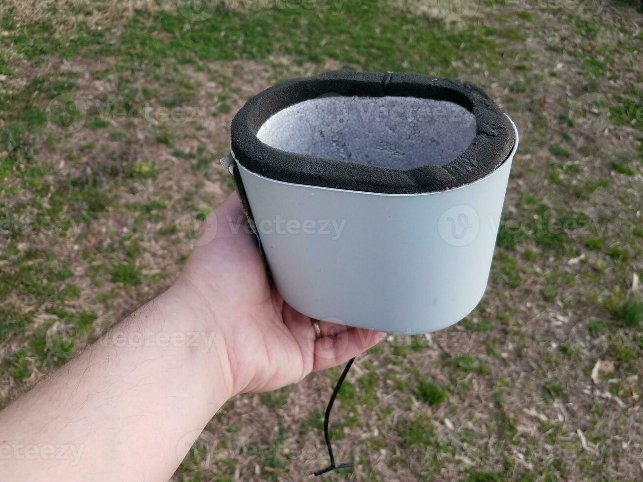hand holding water spigot insulation cap or cover over grass photo
