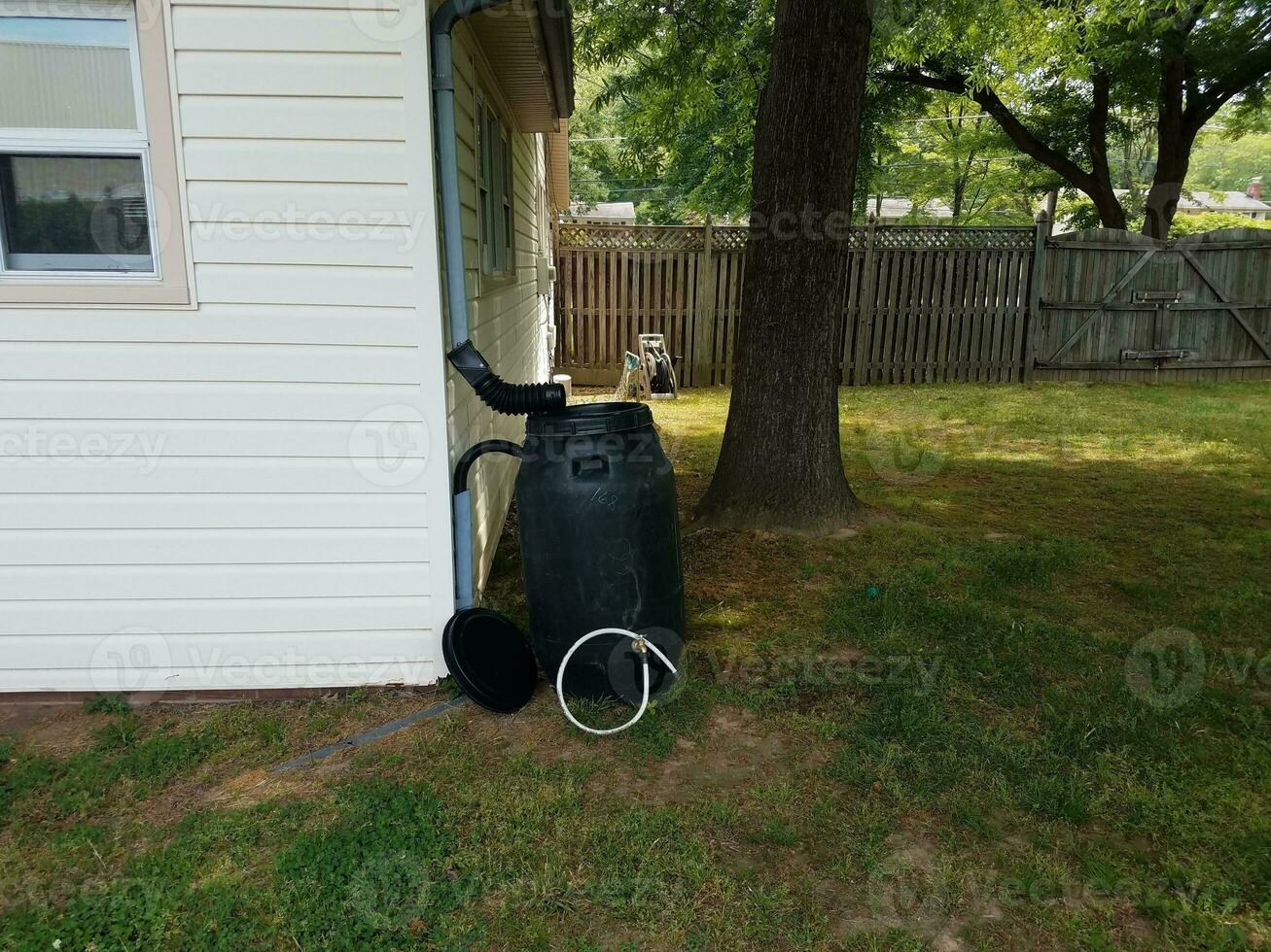 black plastic rain barrel installed on a house photo