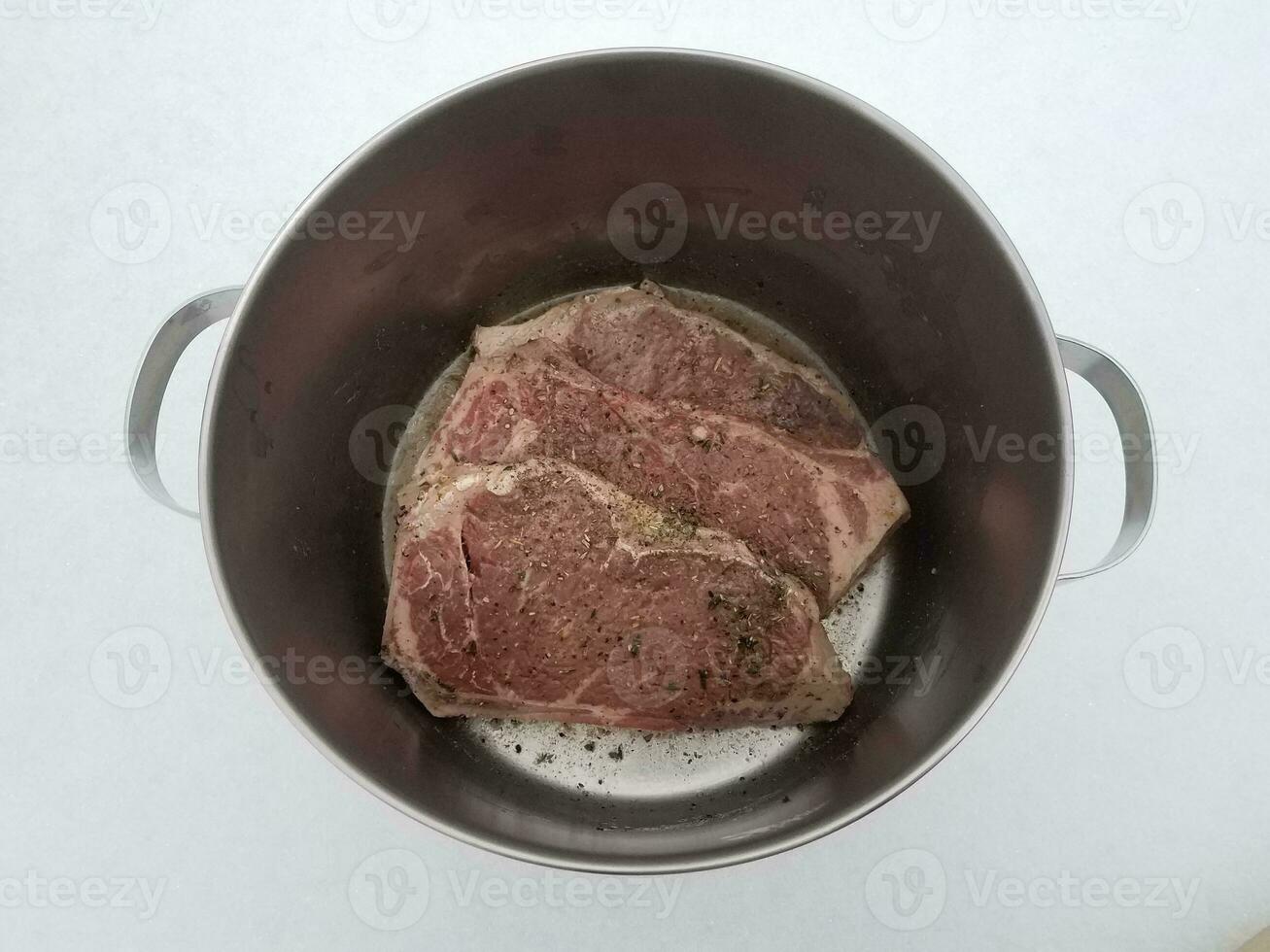 beef steak with seasoning and liquid in metal pot on snow photo