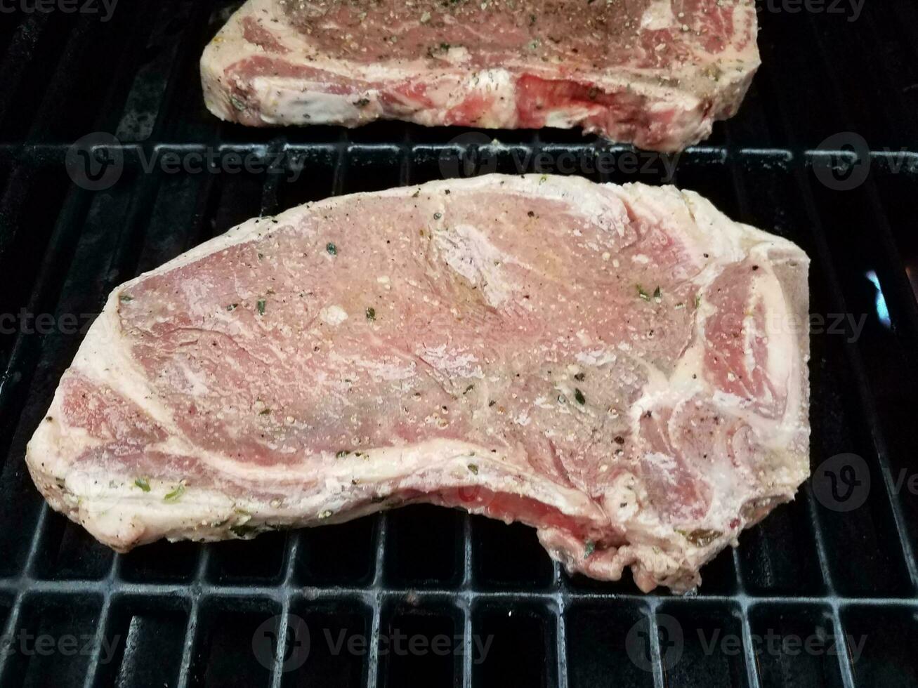 beef steaks with seasoning cooking on barbecue grill photo