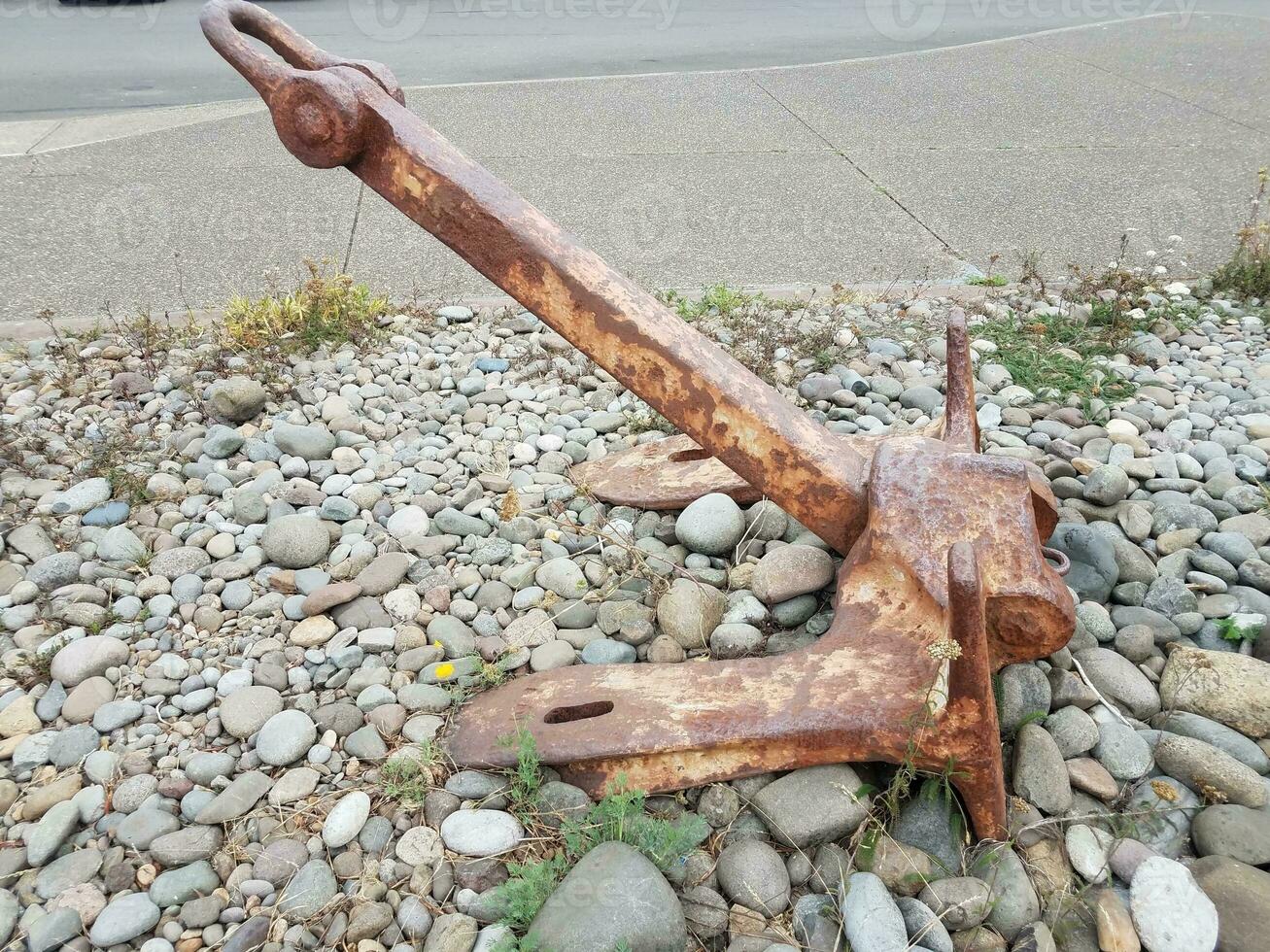 heavy rusty iron anchor on stones or rocks photo