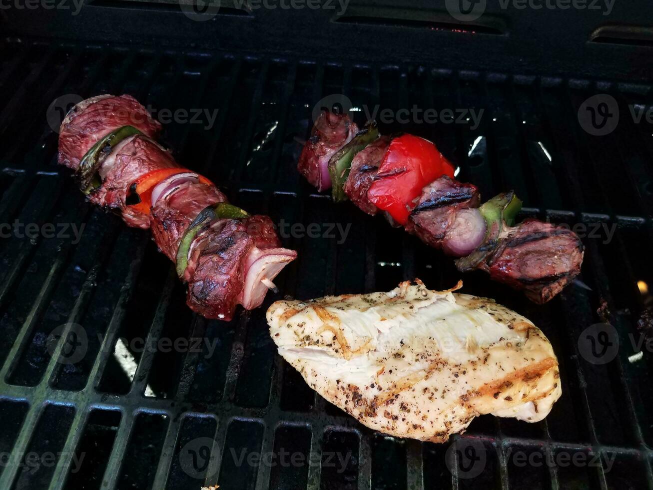beef kebob with onions and peppers on a stick on a grill with chicken photo