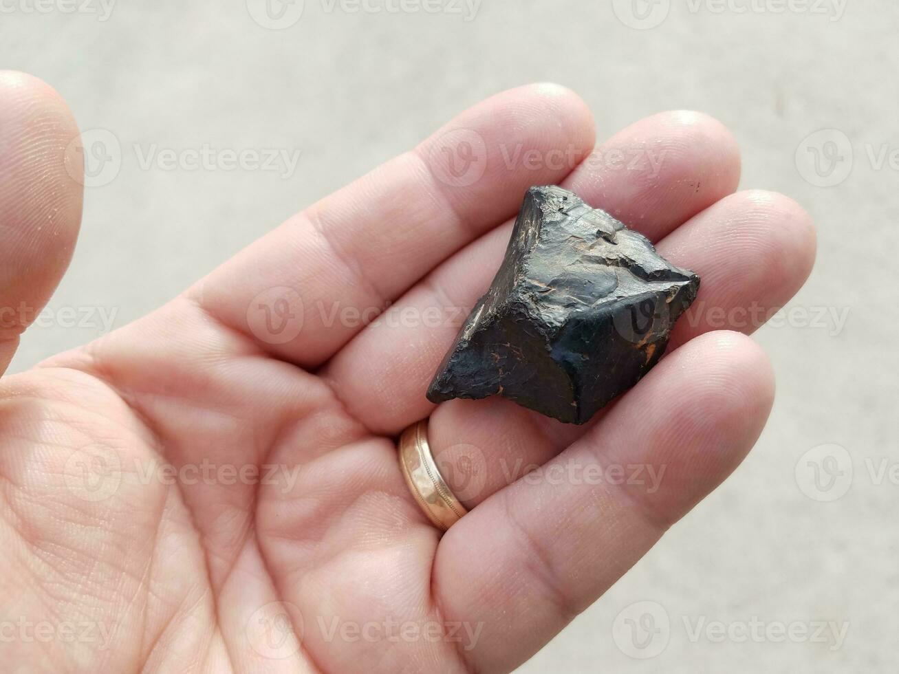 hand holding black burnt piece of wood over cement photo