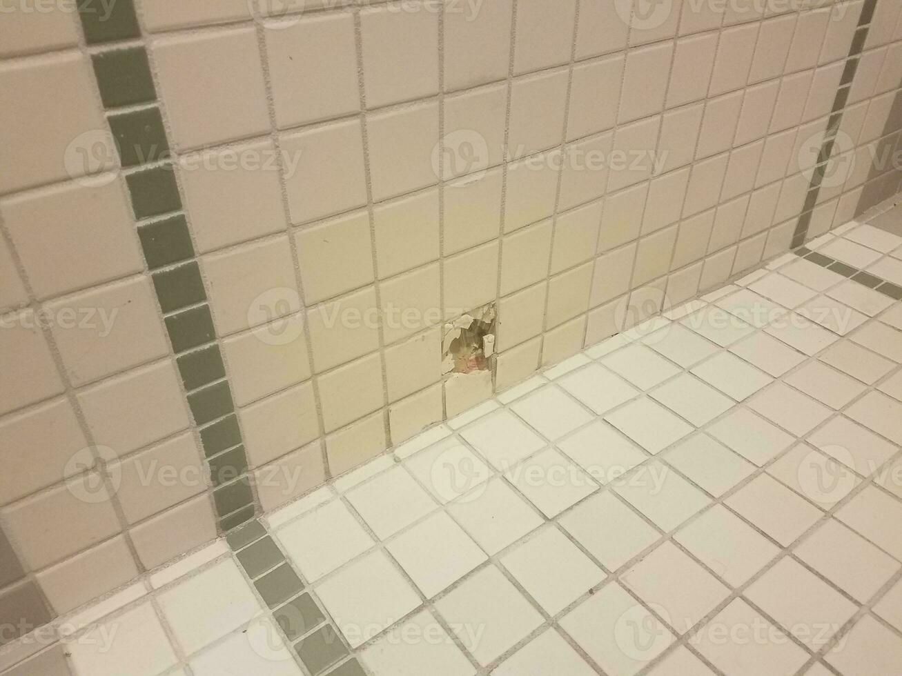 a hole in the white and green bathroom wall tiles photo