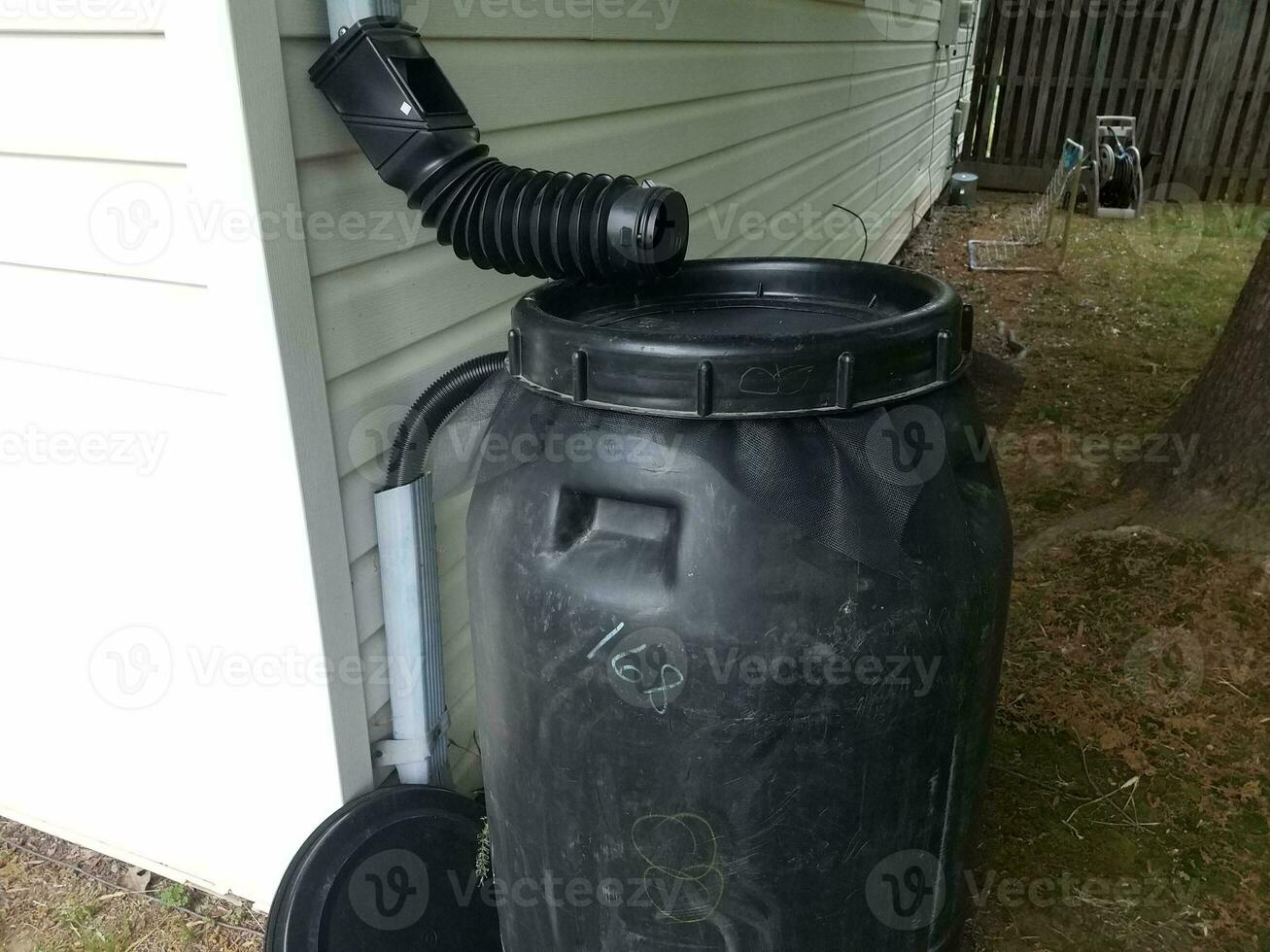 barril de lluvia de plástico negro instalado en una casa foto