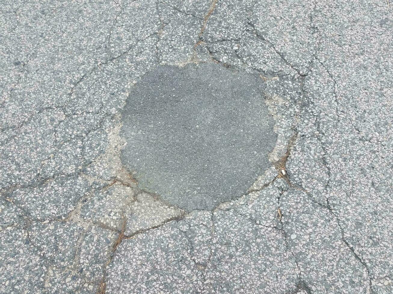 repaired hole in black asphalt with cracks photo