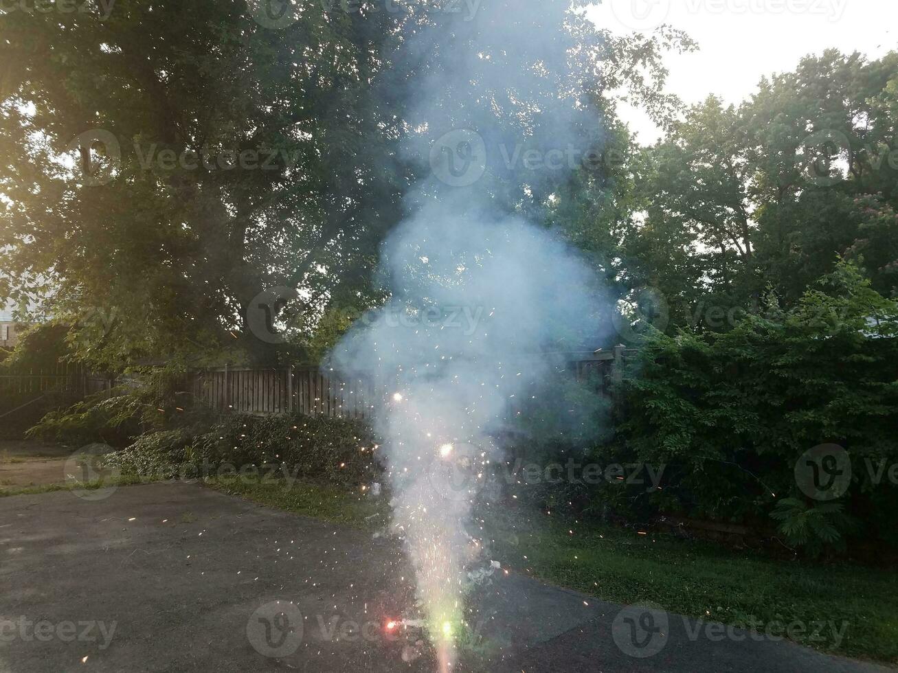 lit colorful fireworks on asphalt driveway with smoke photo