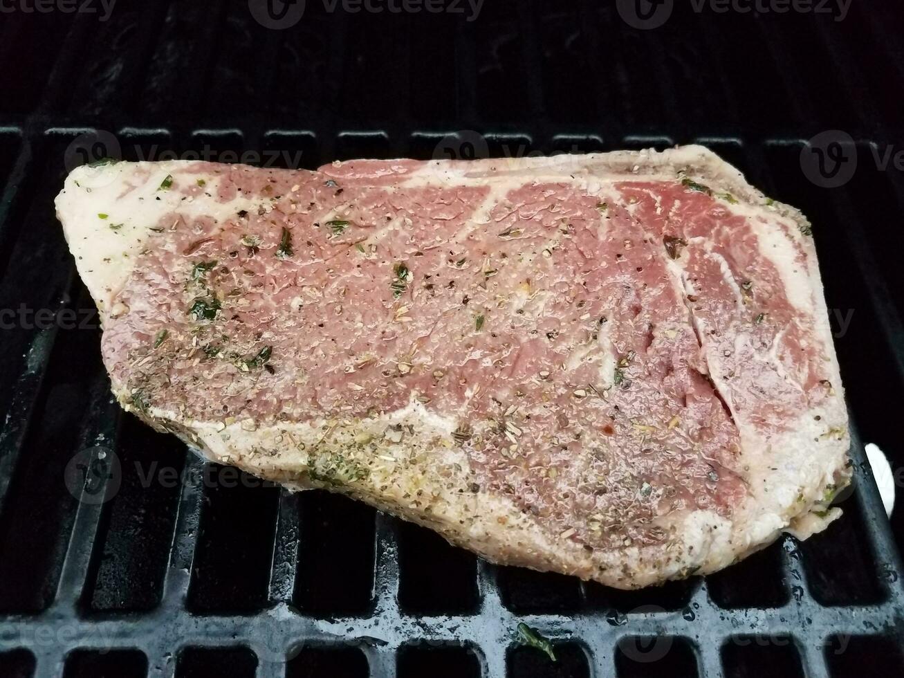 beef steak with seasoning cooking on barbecue grill photo