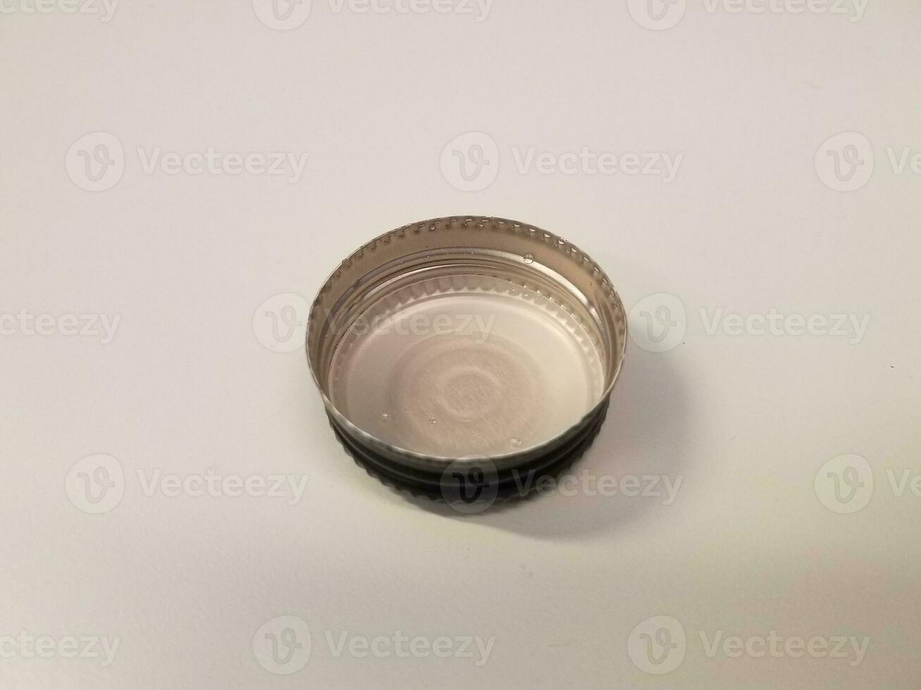 black metal bottle cap on white surface or table photo