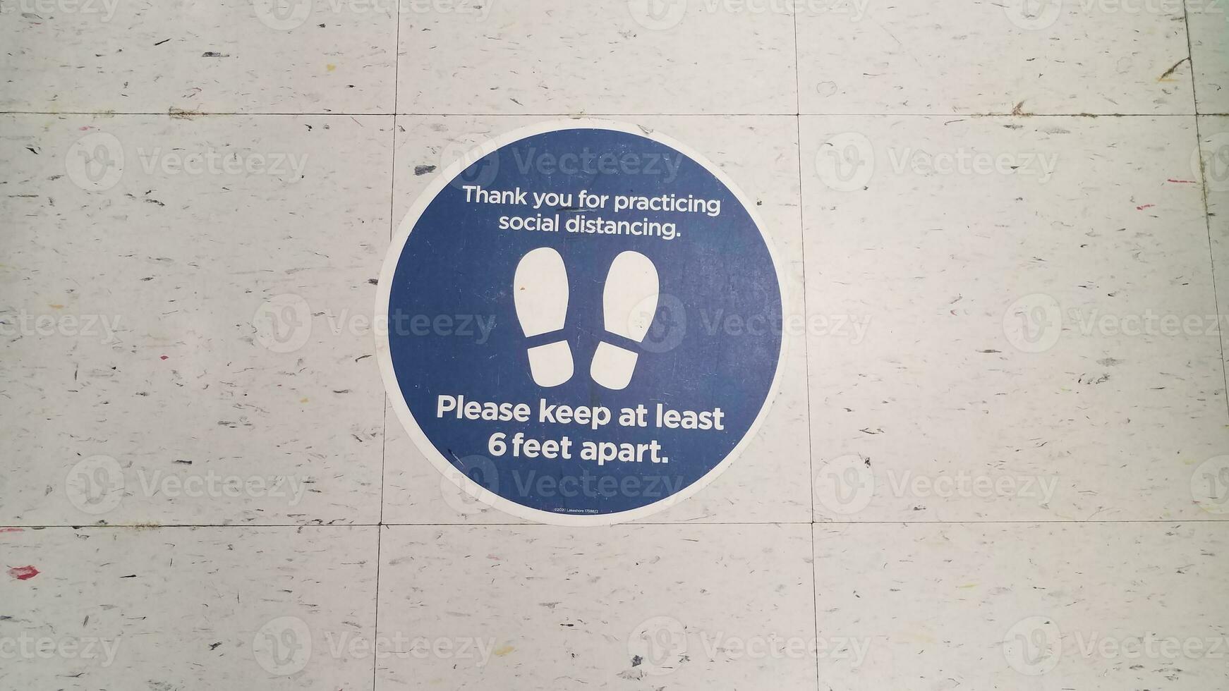 blue please stay six feet apart sign on white tiles photo