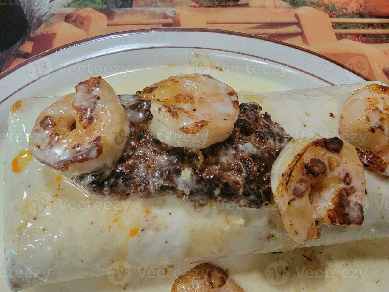 burrito con camarones y carne y crema en placa foto