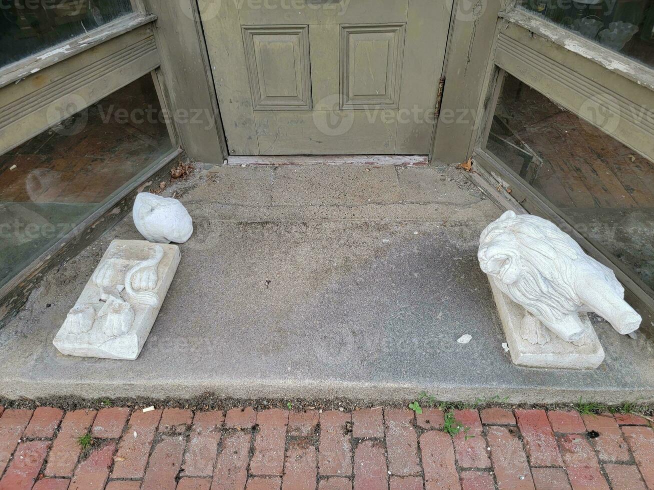 broken or damaged lion statues on the ground with door photo