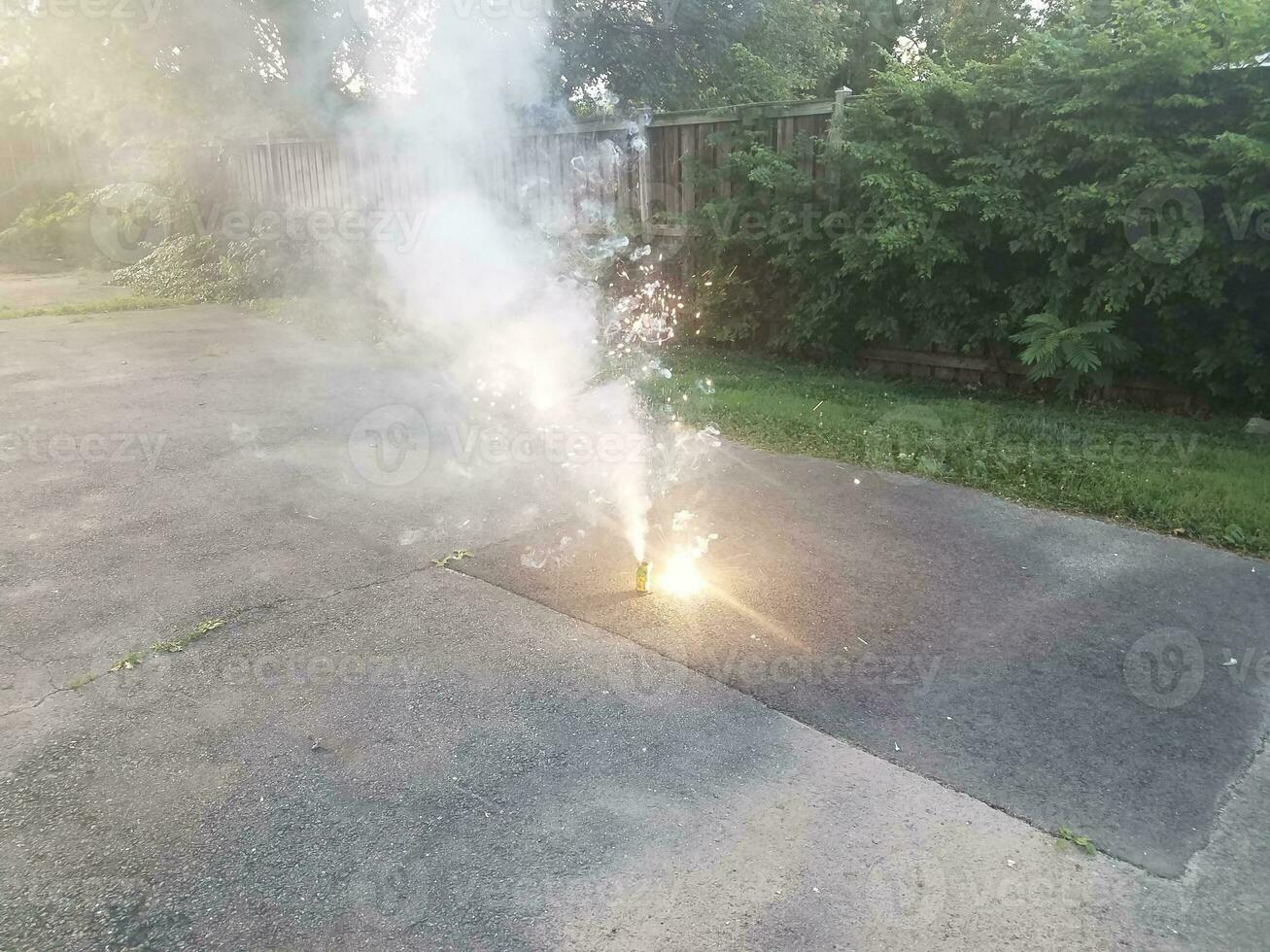 lit colorful fireworks on asphalt driveway with smoke photo