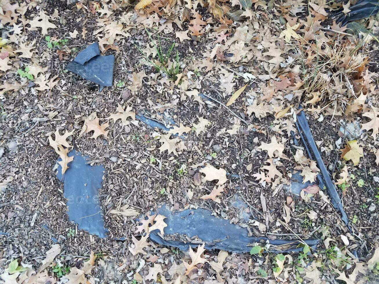 black plastic landscaping fabric and brown leaves photo