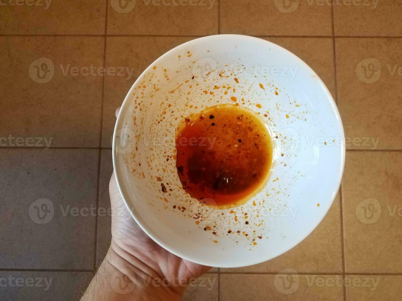 mano sosteniendo aceite rojo en un recipiente de plástico blanco foto