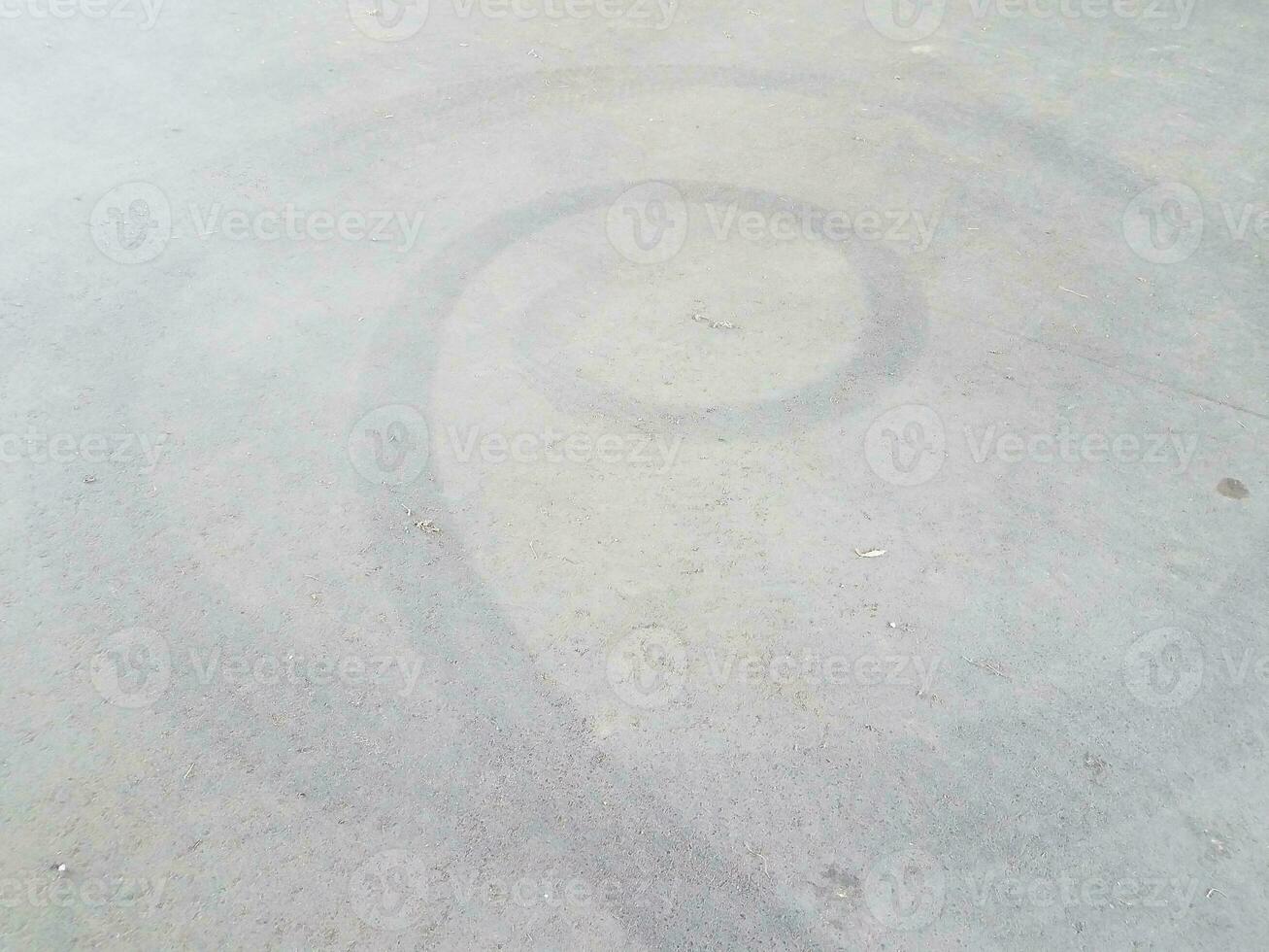 black spiral skidmark on black asphalt or pavement photo