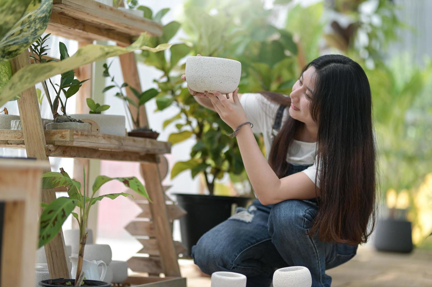 mujer joven cuidando árboles, equipo de plantación y cuidado, plantas en invernaderos, pequeñas empresas. foto