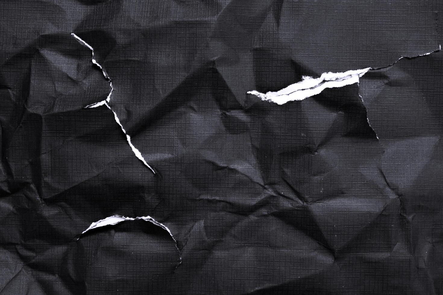 Black paper with white tears for the background. Crumpled paper texture with messy tears. photo