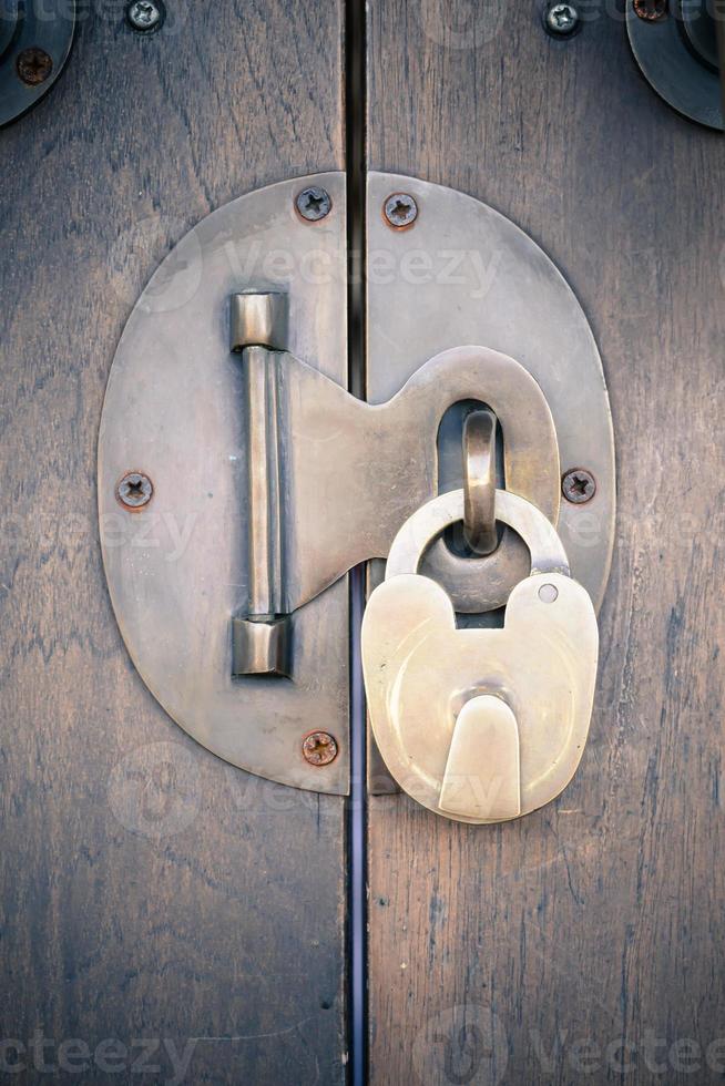 Ancient brass lock on wooden door with handle photo