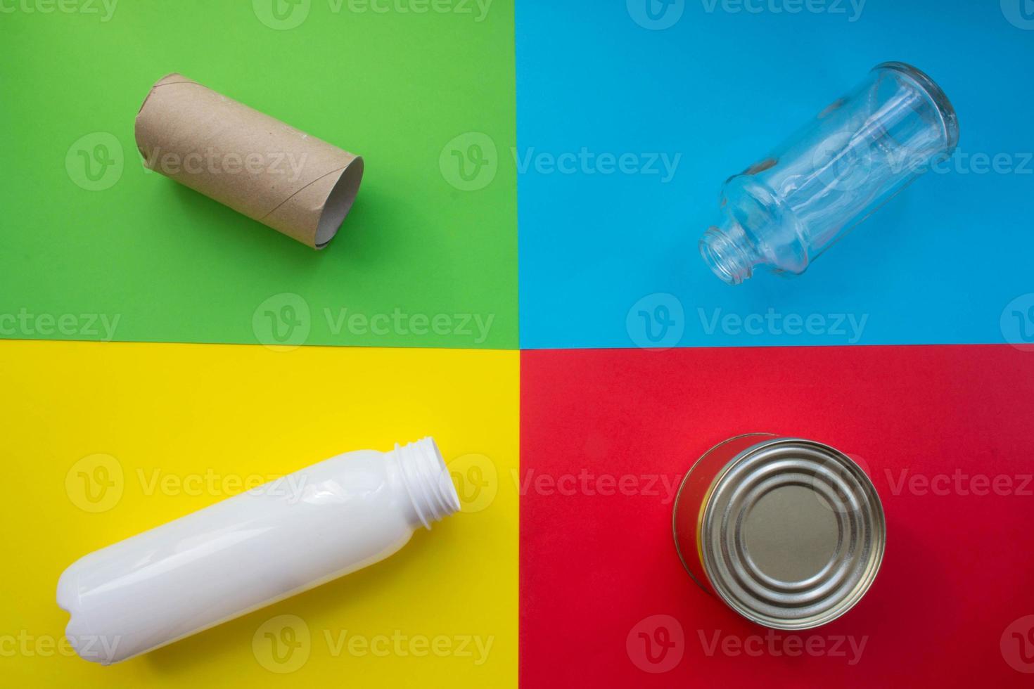concepto de reciclaje de clasificación de residuos. botella de vidrio, lata de metal, botella de plástico y manga de papel higiénico sobre un fondo colorido foto