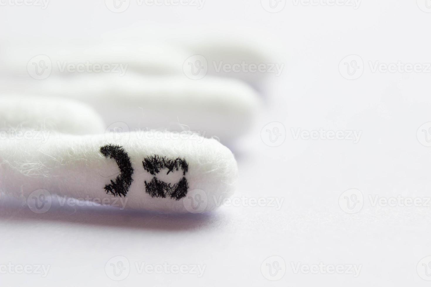 Close-up of cotton swabs with a sad emoticon on a cotton swab in the foreground. photo